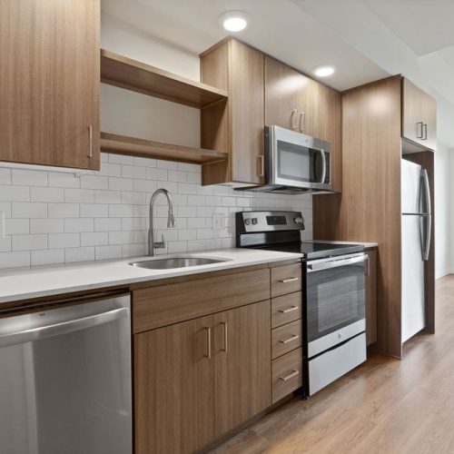 Modern kitchen with wood cabinets, white subway tile backsplash, stainless steel appliances, and light wood flooring.